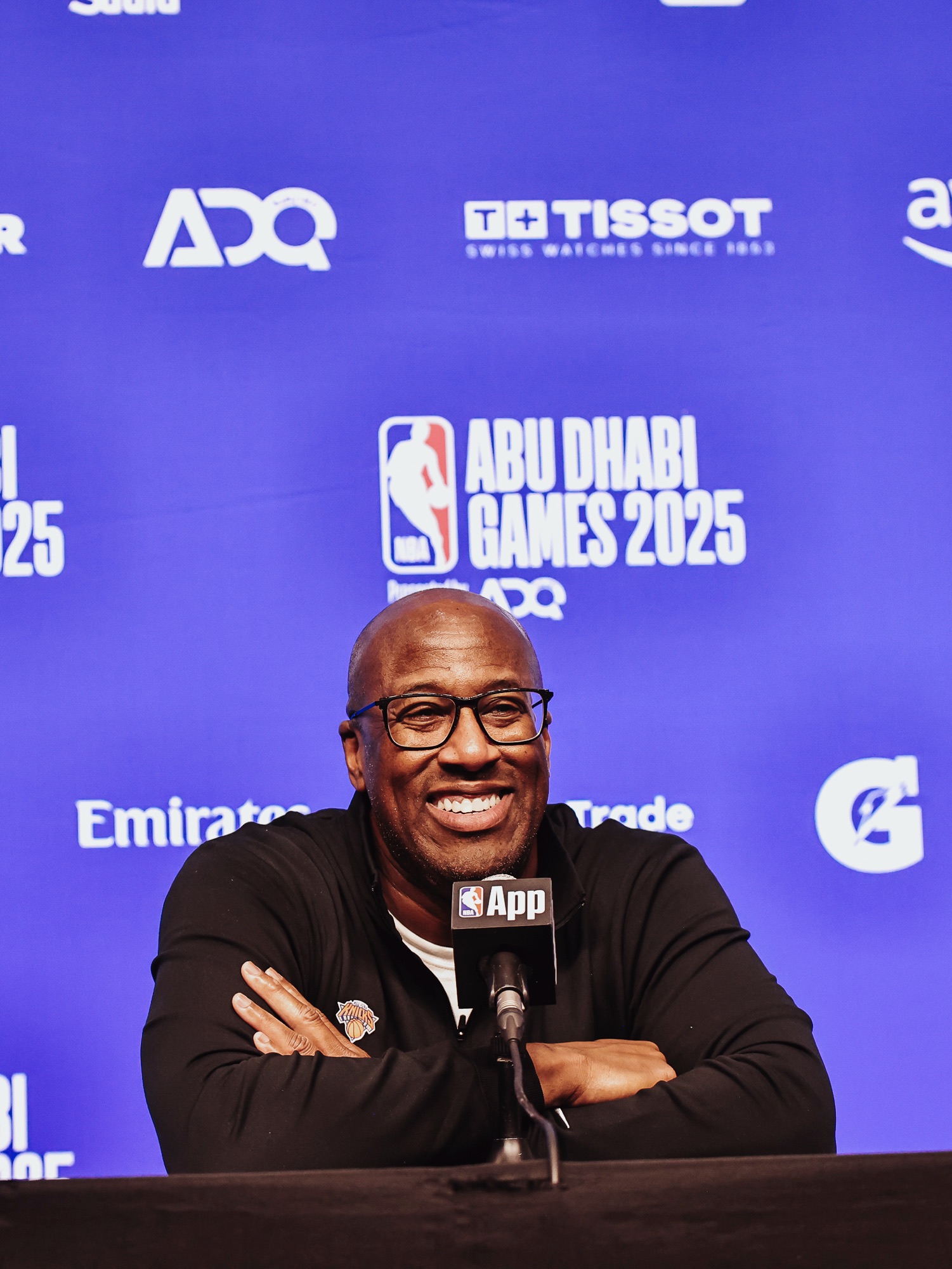 Smiling coach in a black top at a press conference in front of an Abu Dhabi Games backdrop