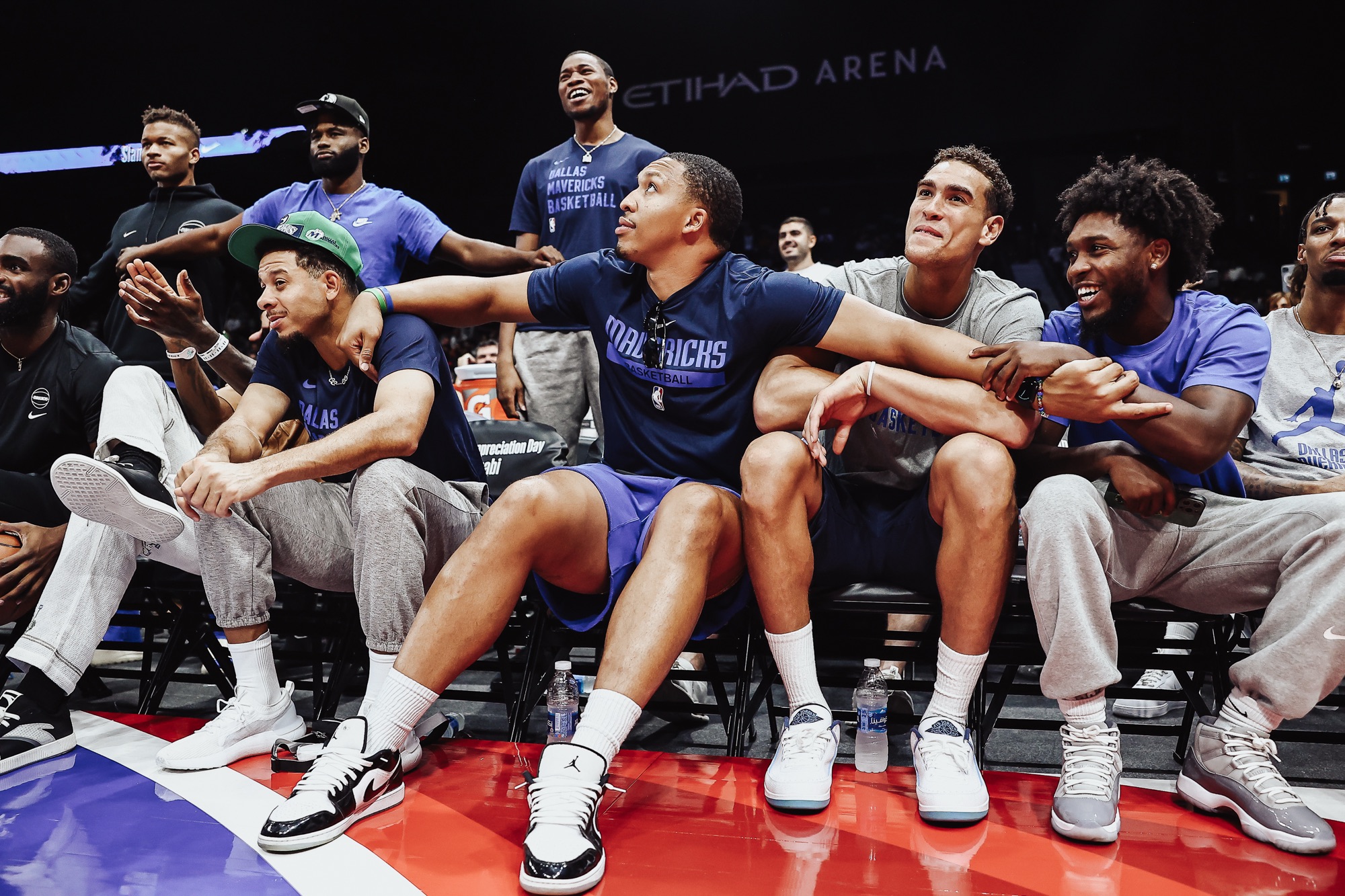 Dallas Mavericks players laughing and cheering together courtside at Etihad Arena