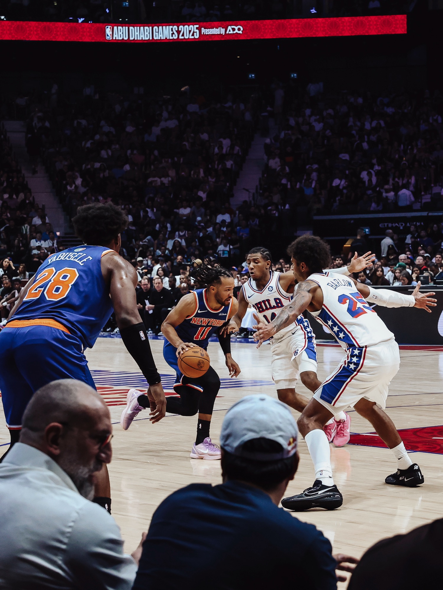 New York No. 11 driving with the ball past Philadelphia defenders, courtside view