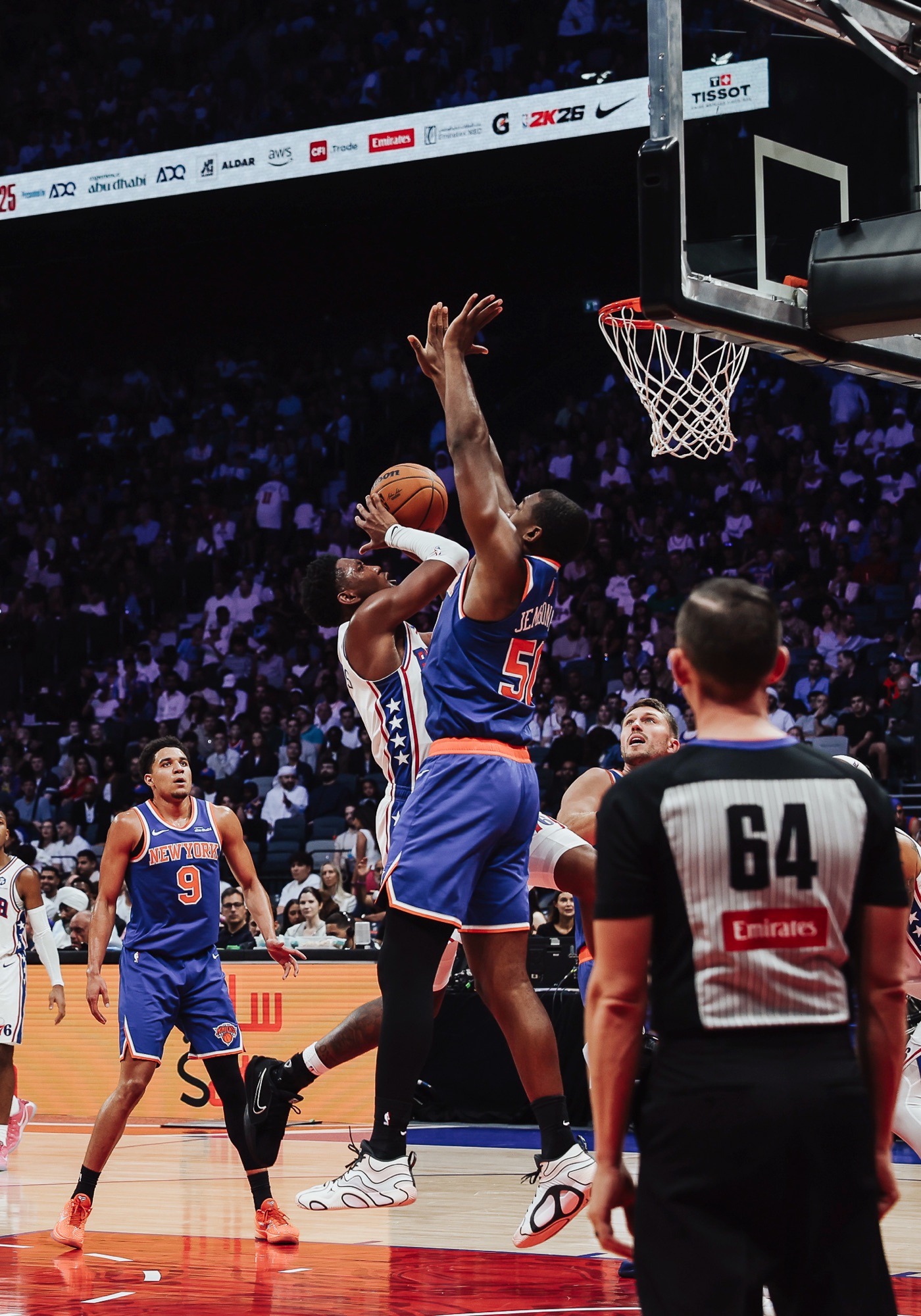 New York No. 50 contesting a Philadelphia shot near the basket as a referee watches