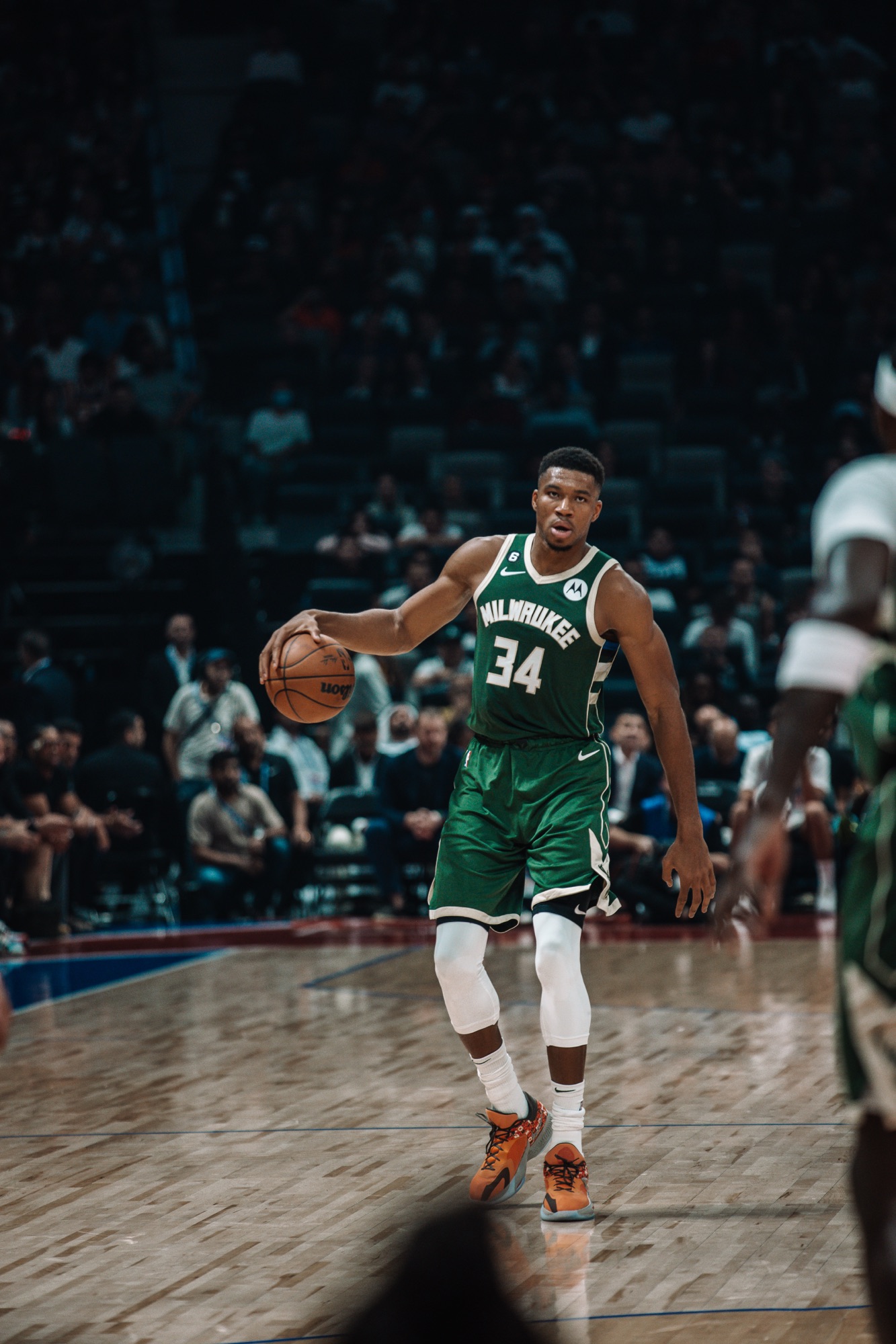 Player in a green Milwaukee No. 34 jersey dribbling the ball up the court