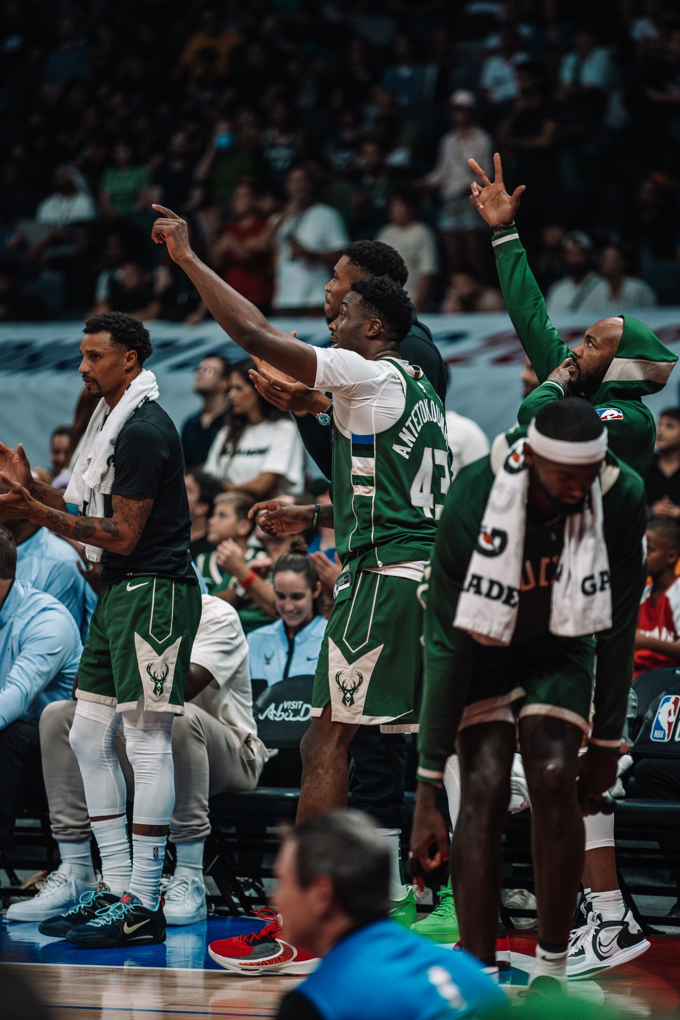 Milwaukee bench players in green standing and cheering with fingers raised