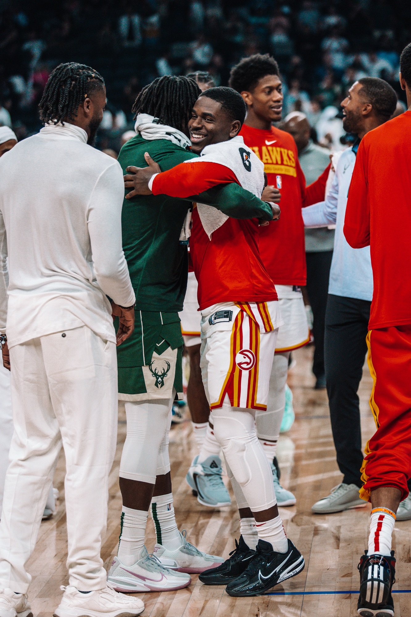Atlanta and Milwaukee players hugging and smiling on court after a game