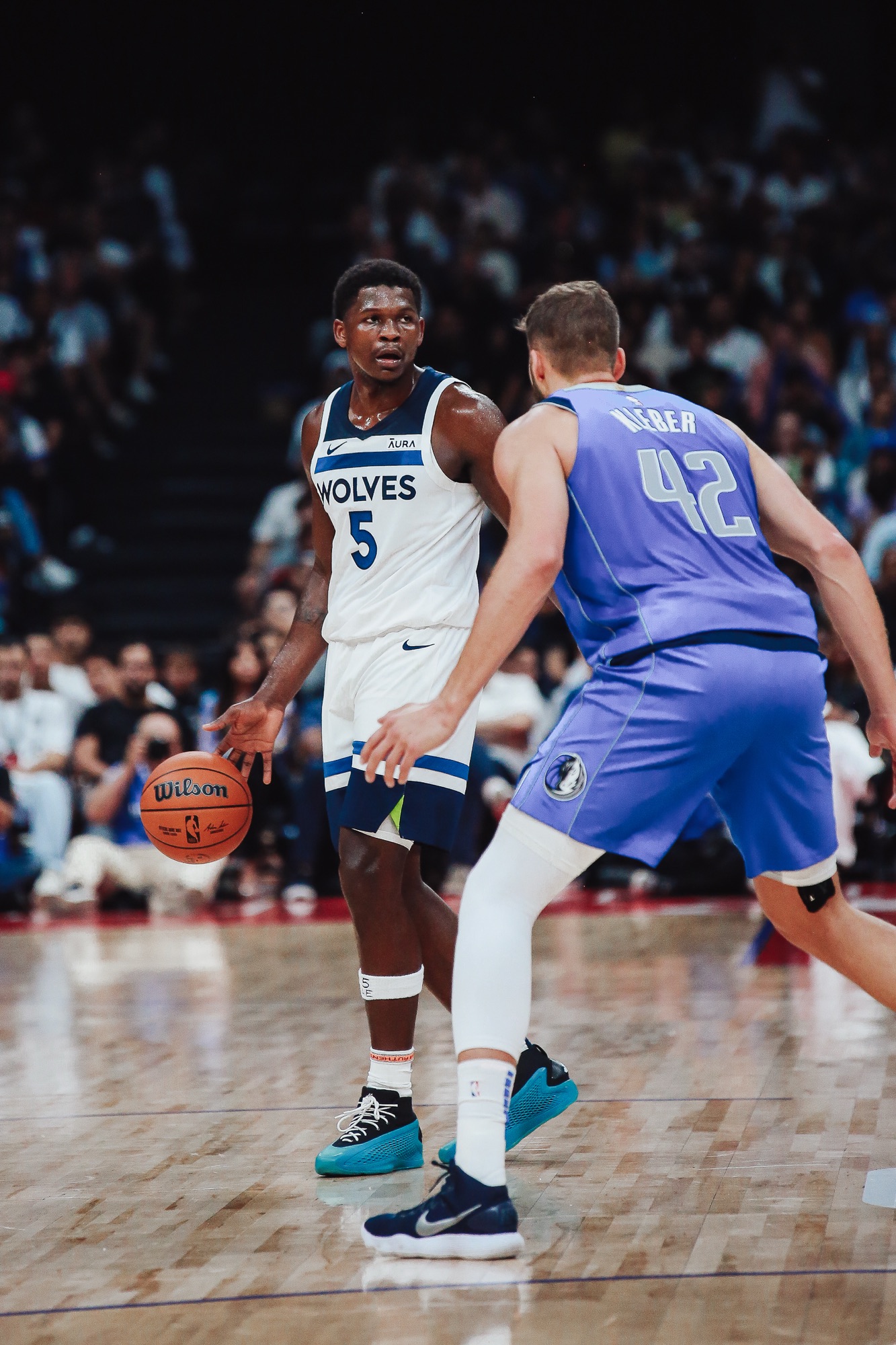 Player in a white Wolves No. 5 jersey dribbling against a Dallas defender