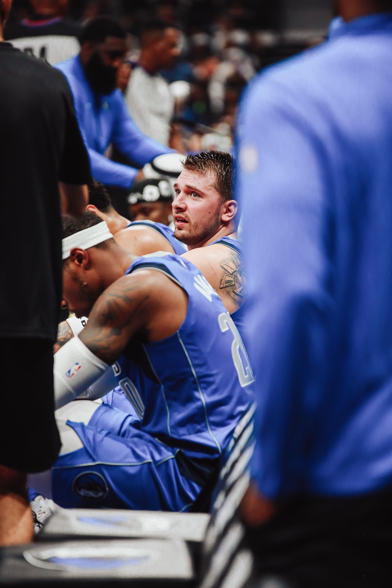 Dallas players in blue jerseys seated in a timeout huddle on the bench