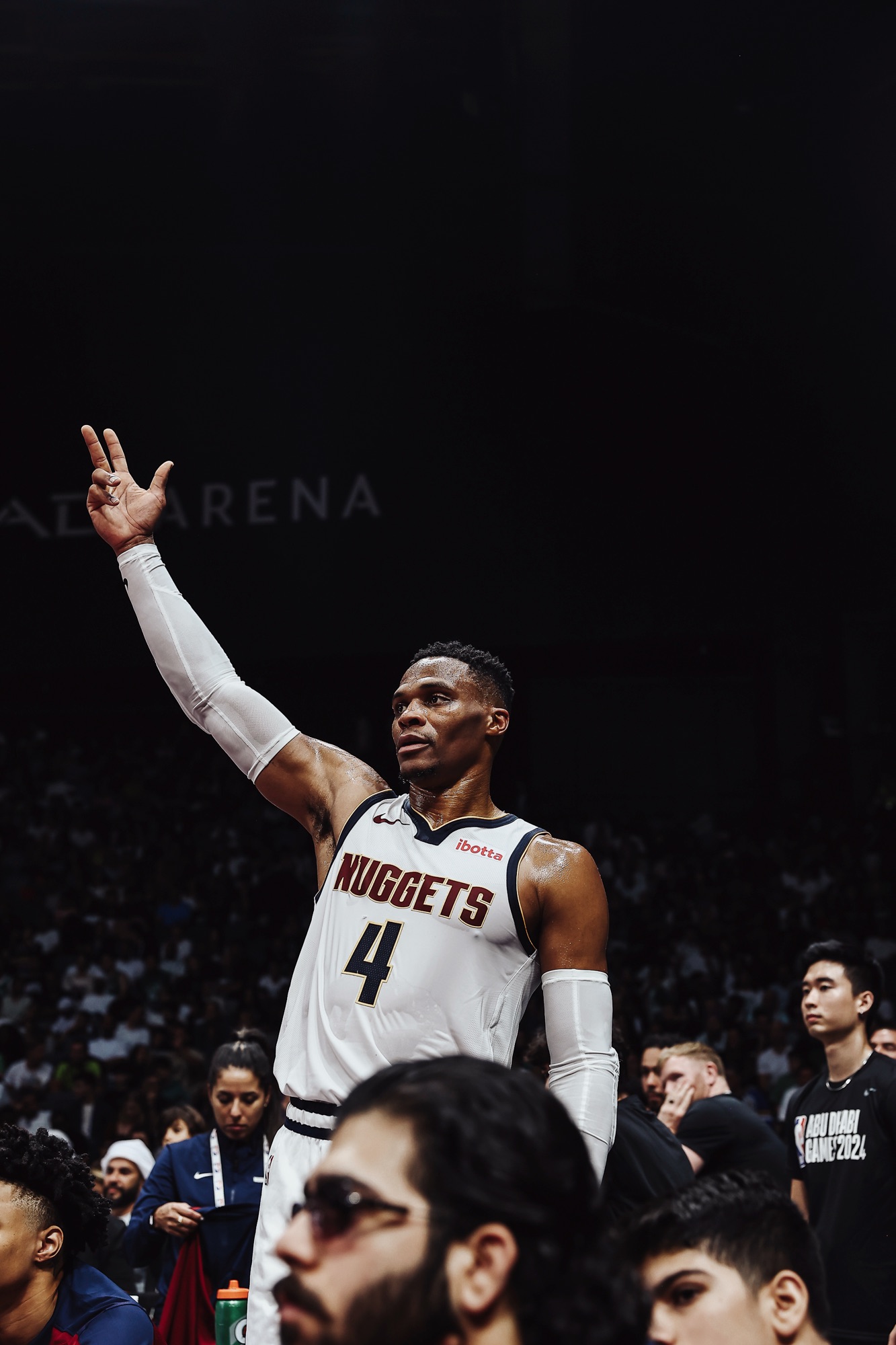 Player in a white Nuggets No. 4 jersey raising two fingers to the crowd