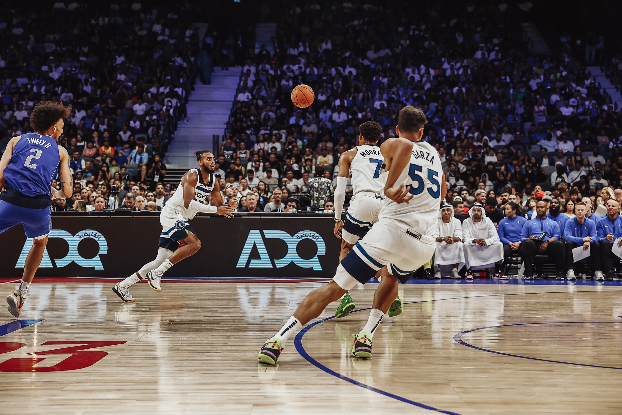 Wolves players in white moving the ball upcourt in a packed arena, wide view