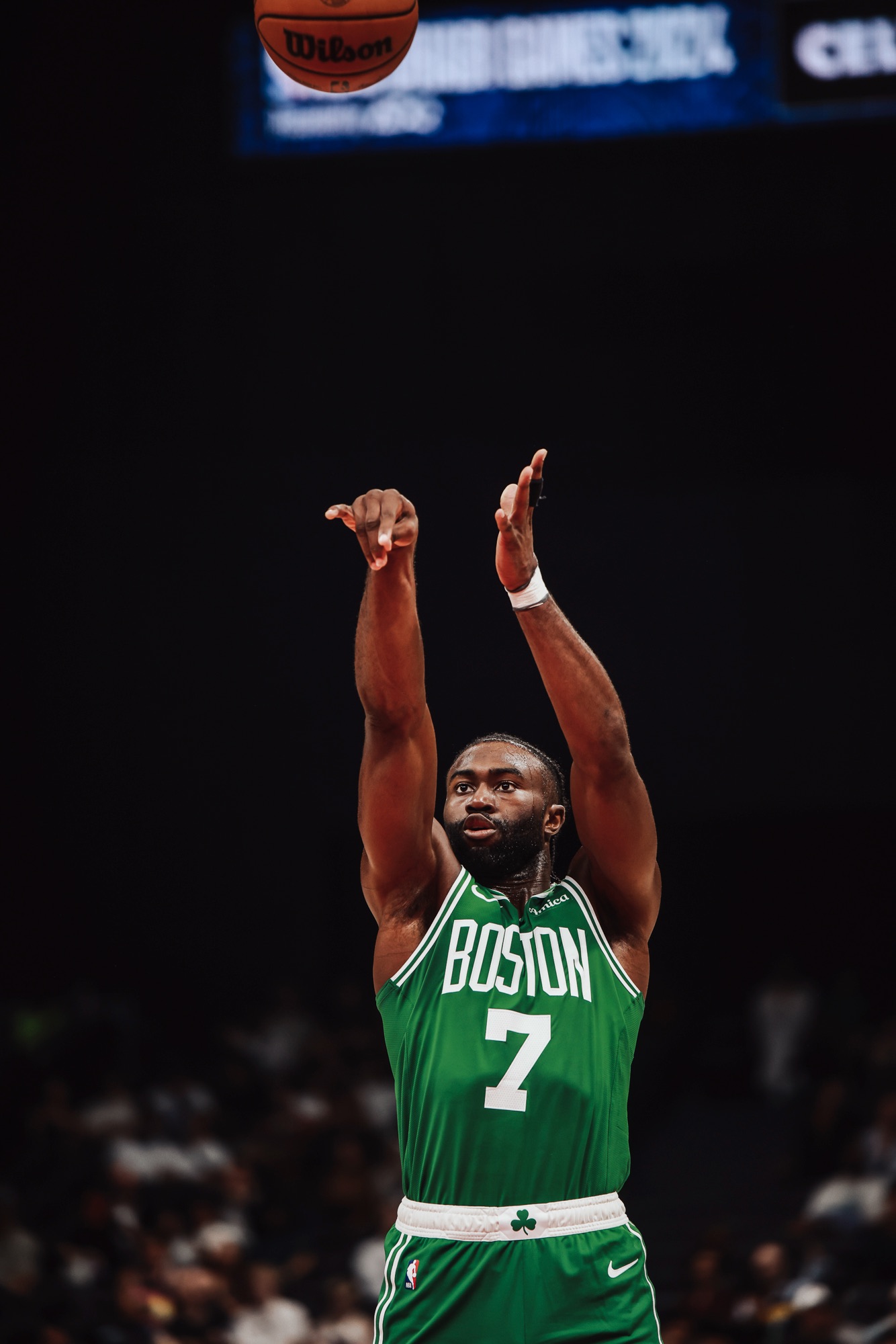 Player in a green Boston No. 7 jersey releasing a jump shot against a dark backdrop