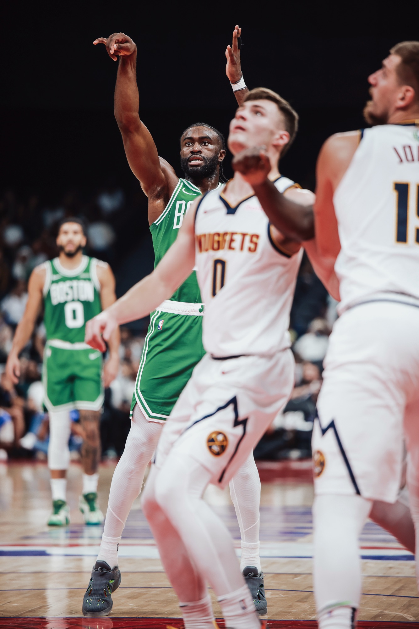 Boston player in green following through on a free throw as Nuggets players watch