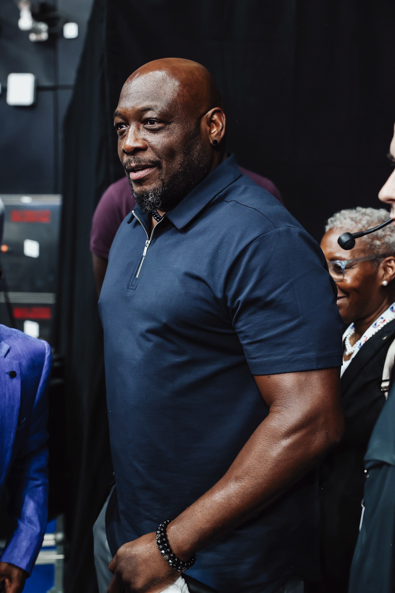 Smiling man in a navy polo shirt walking backstage at the arena