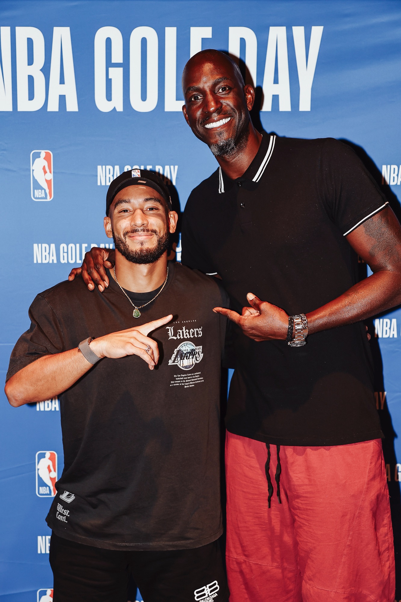 Two smiling men posing together in front of an NBA Golf Day backdrop