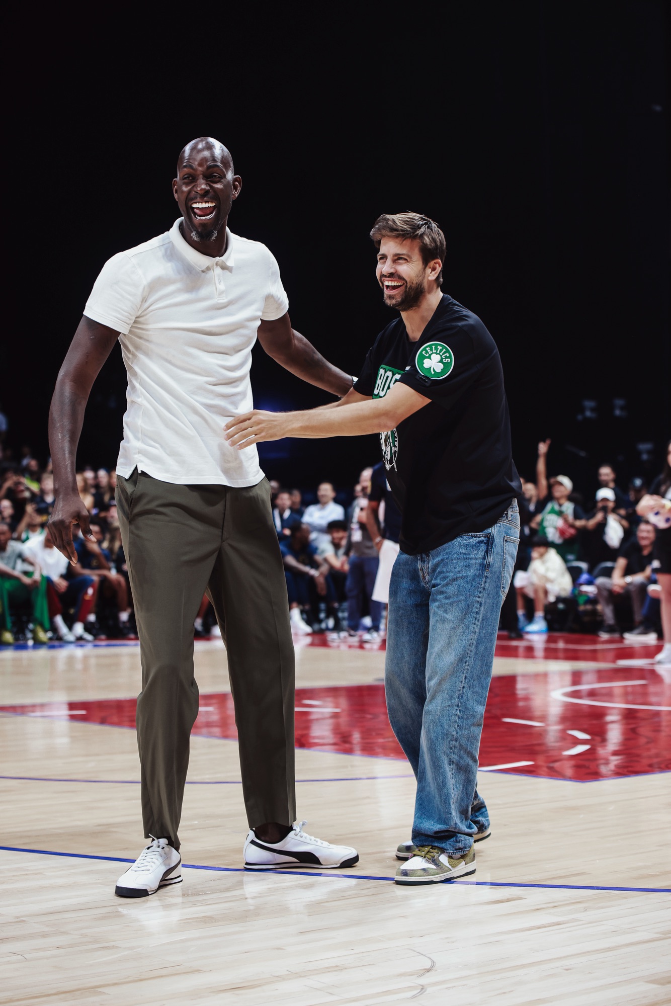 Two men laughing together on court, one in a black Celtics T-shirt