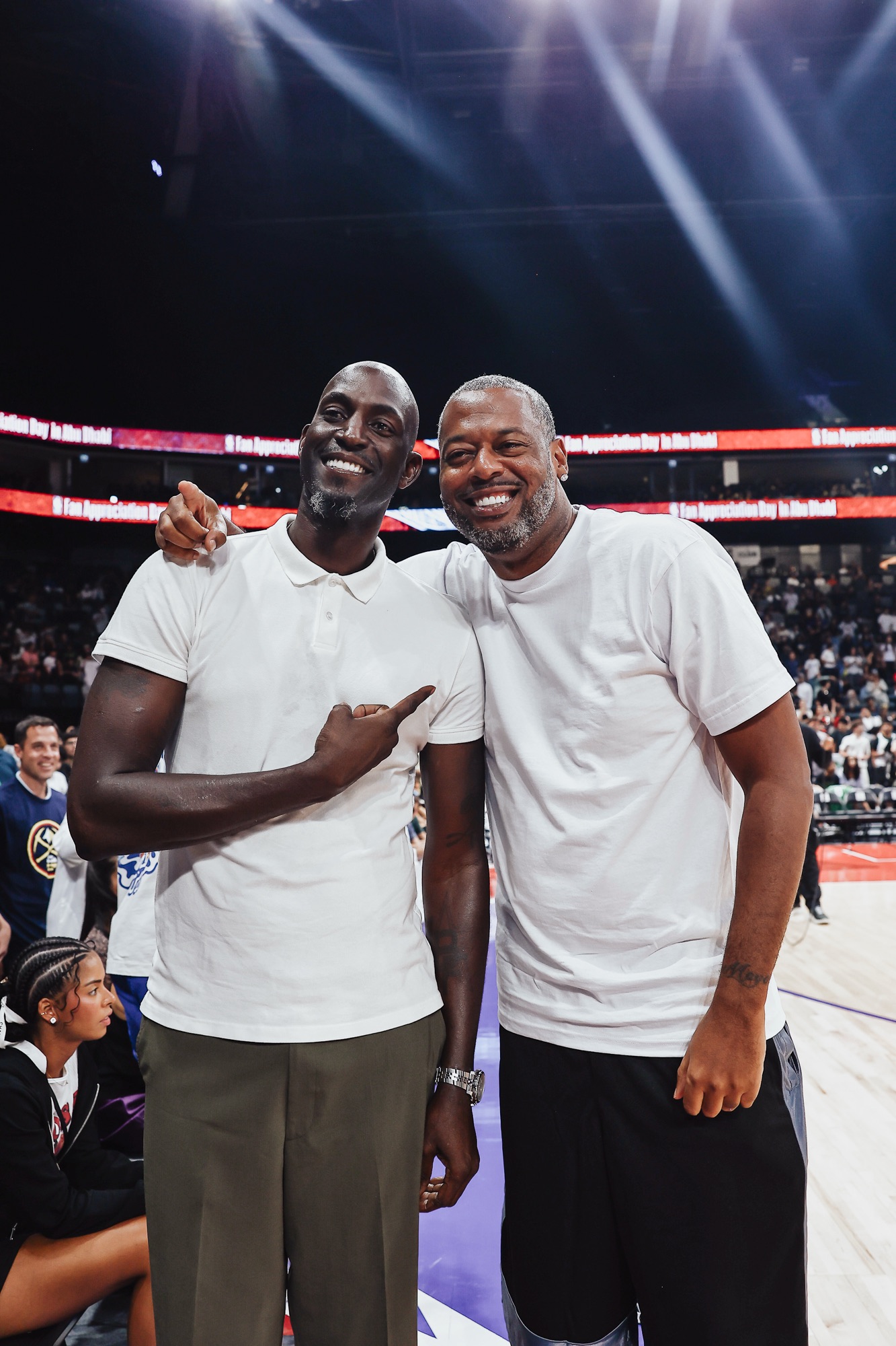 Two smiling men in white shirts posing arm in arm on court