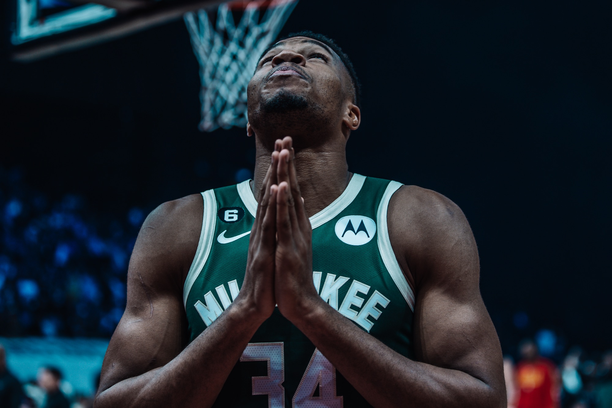 Player in a green Milwaukee jersey with hands pressed together, looking upward