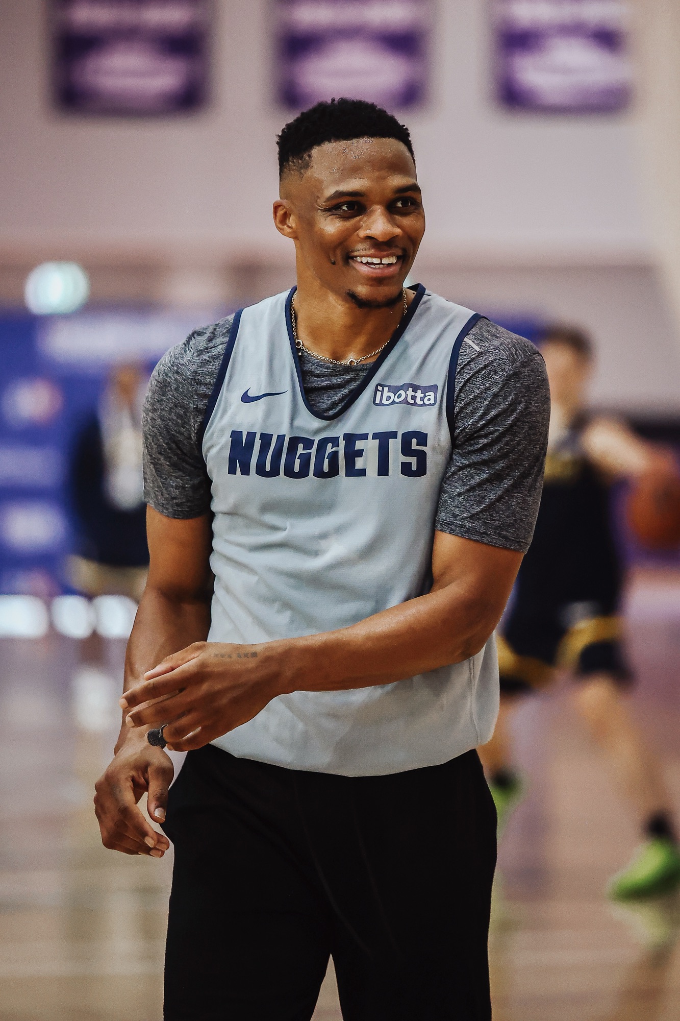 Smiling player in a grey Nuggets practice jersey on the training court