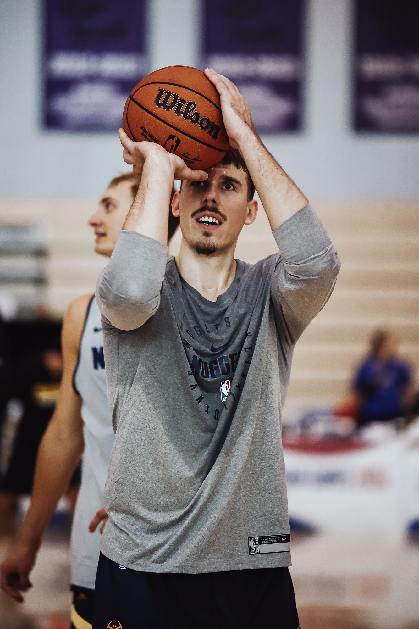 Player in a grey Nuggets shirt lining up a shot during practice