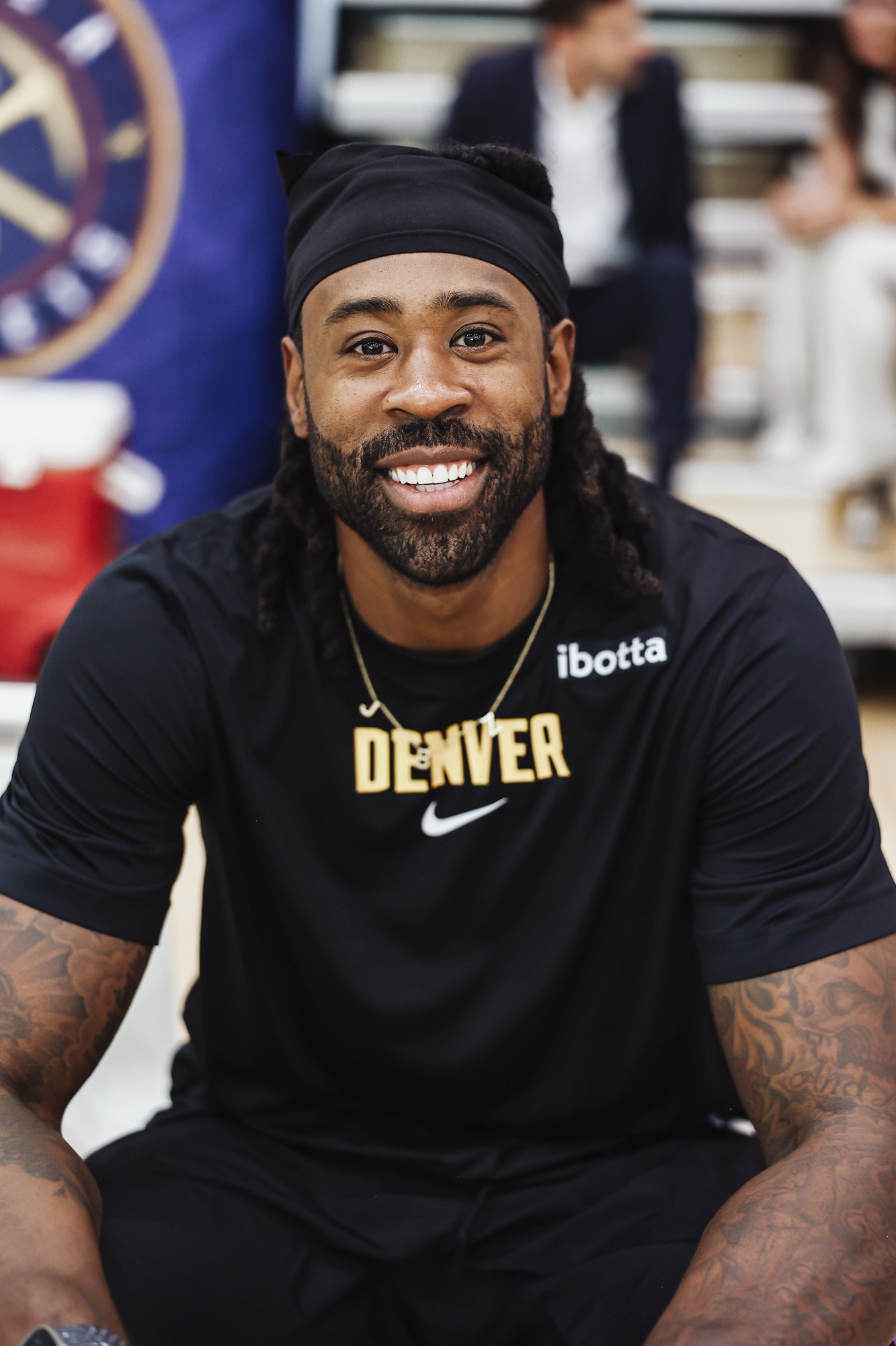 Smiling man in a black headband and Denver T-shirt, close-up portrait