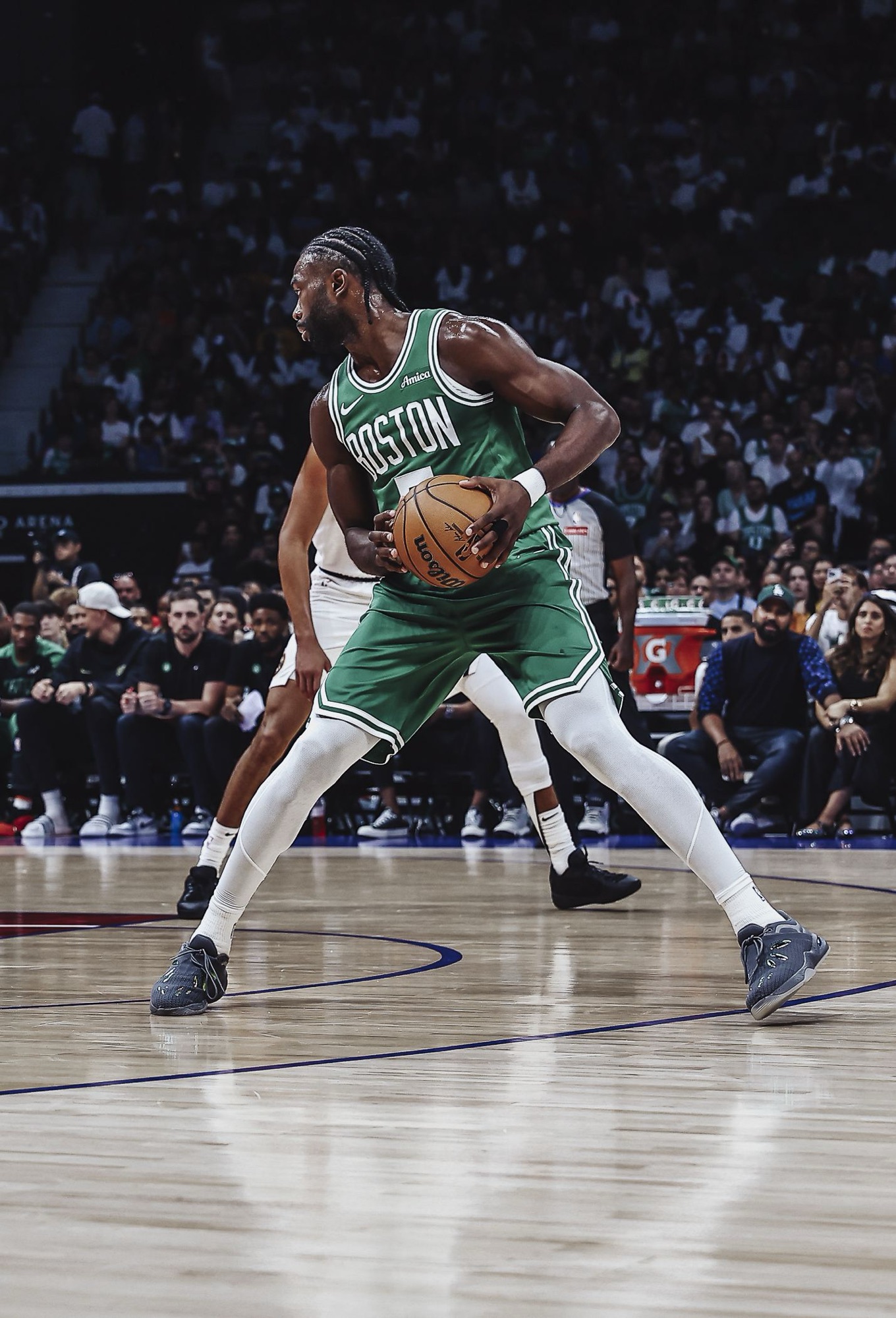 Basketball player in a green Boston jersey driving with the ball during an arena game