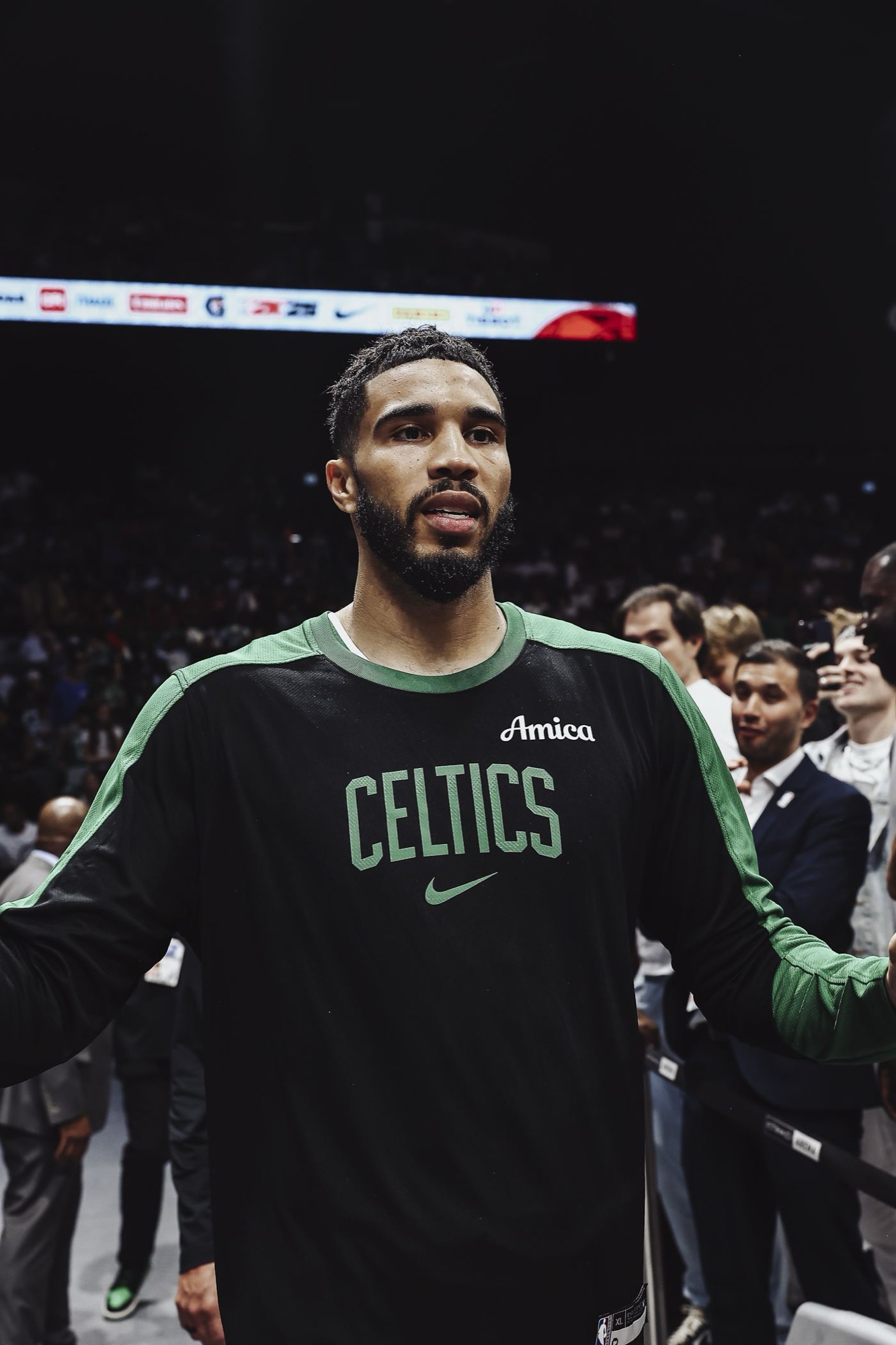 Player in a black Celtics warm-up shirt on court before a game