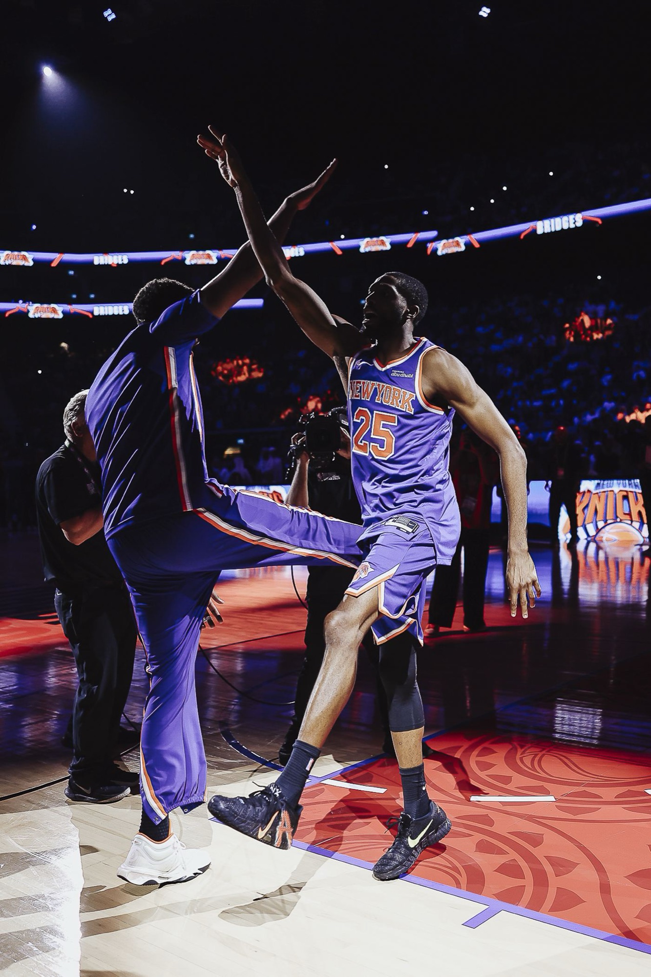 Player leaping for a high-five during warm-ups under arena lights