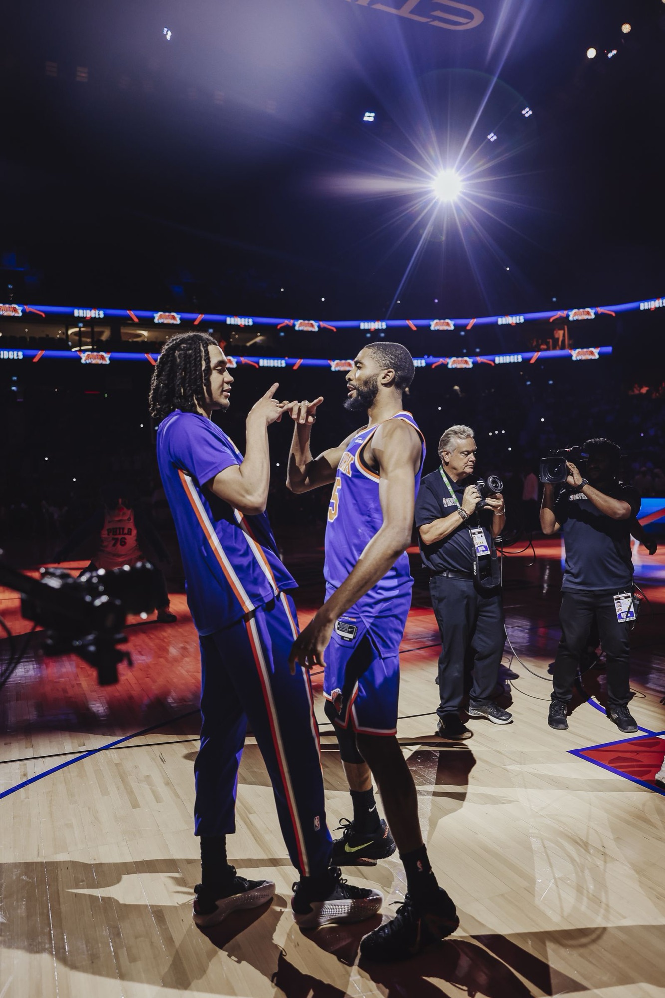Players and staff on court under arena spotlights
